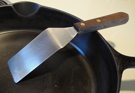 stainless steel spatula resting in a cast iron skillet