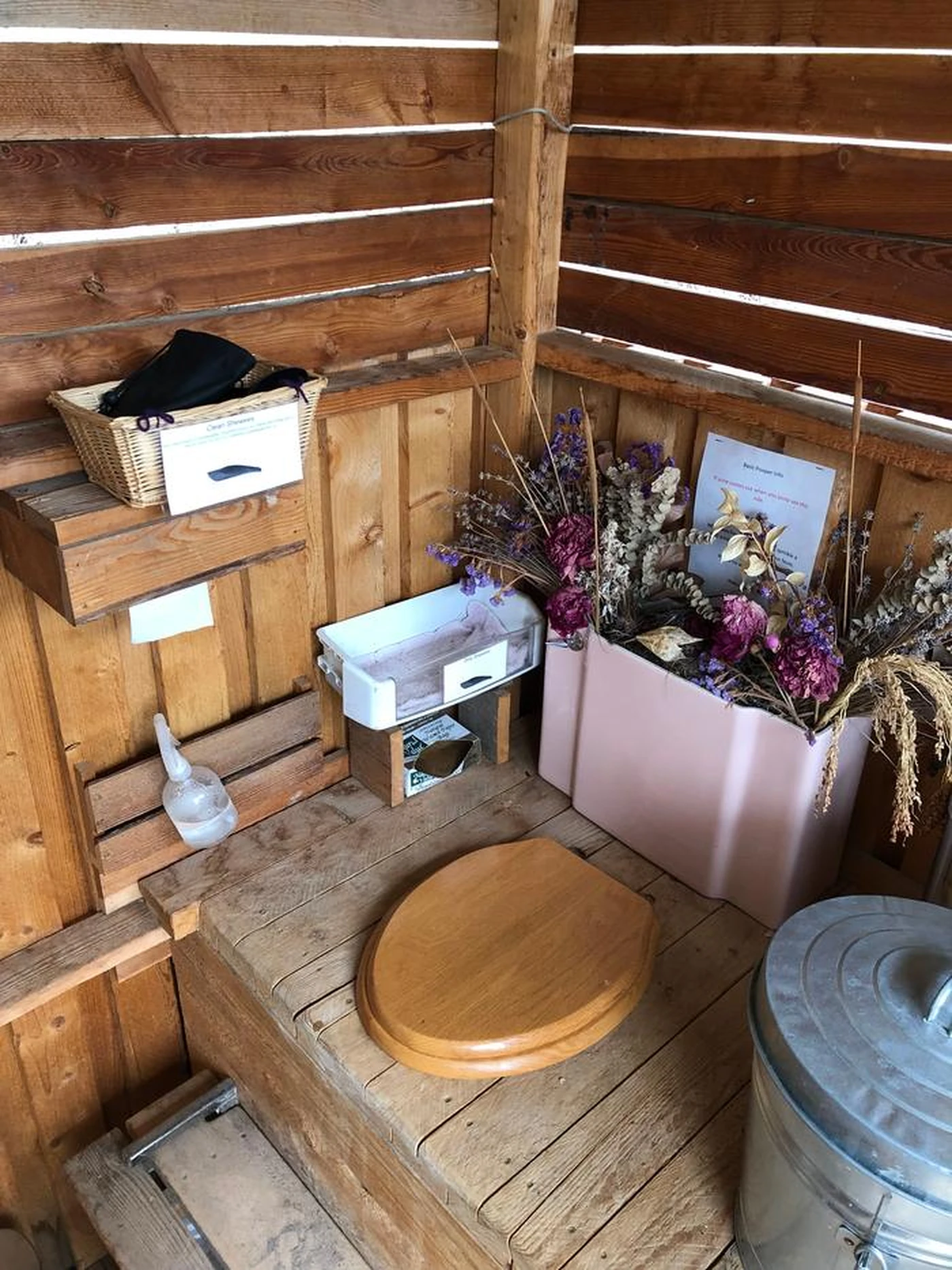 Interior of a Willow Feeder with a wooden seat, collection can, and vented cabin wall